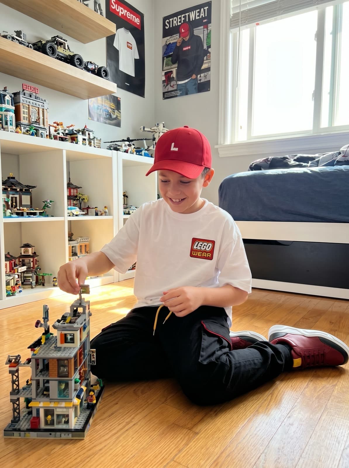 A child in a LEGO Wear t-shirt and red cap building a LEGO set at home