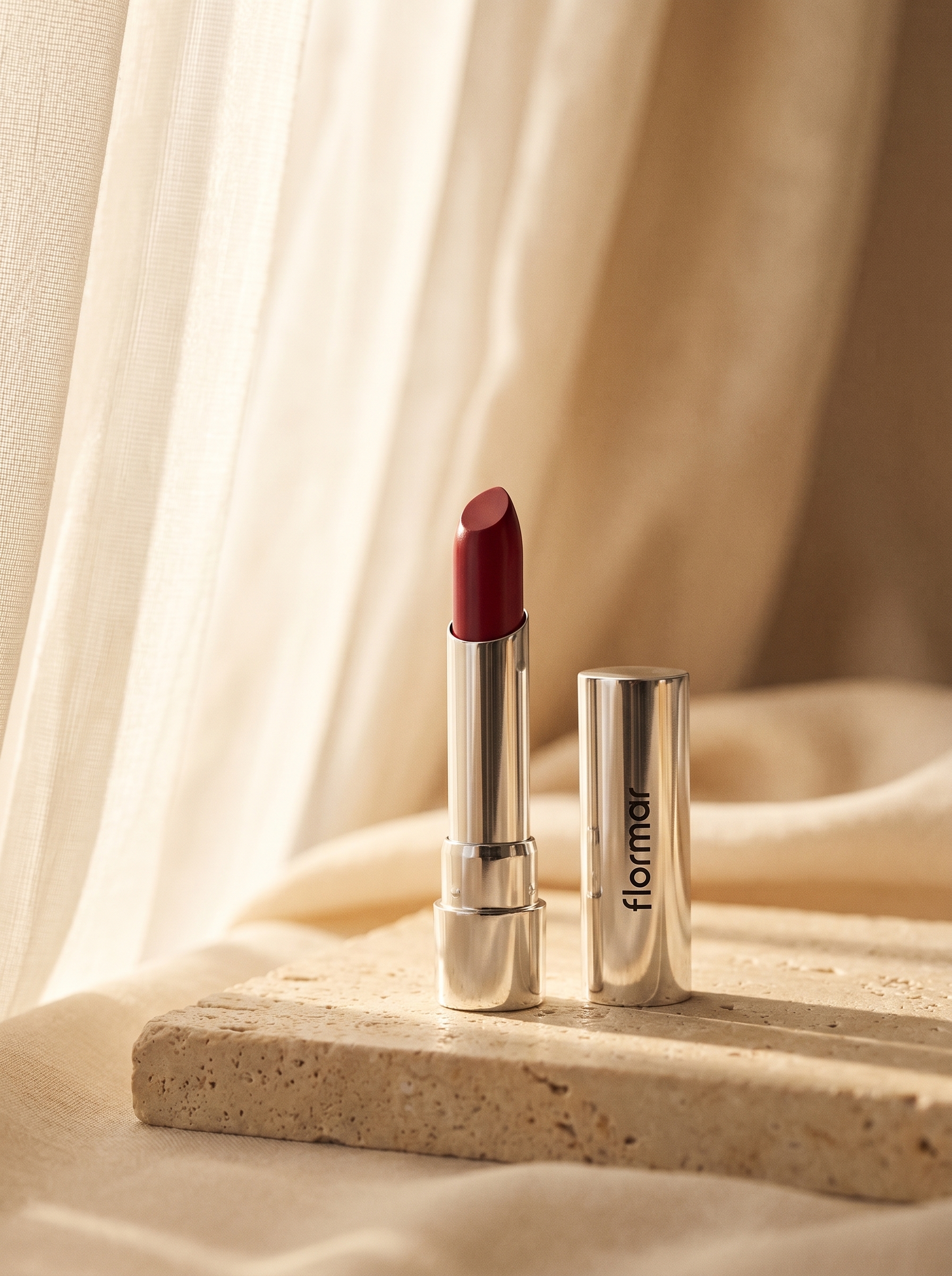 A lipstick shot in warm light in front of a curtain